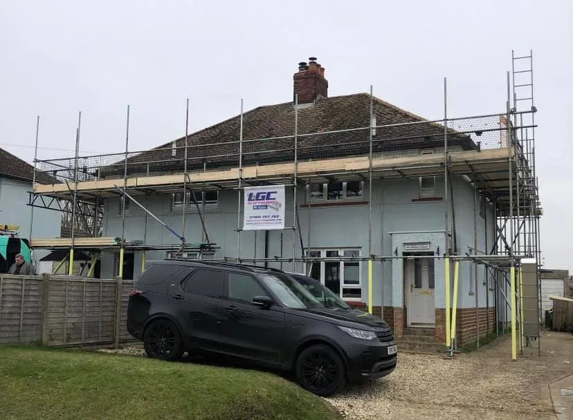 A car parked in front of a house under construction.
